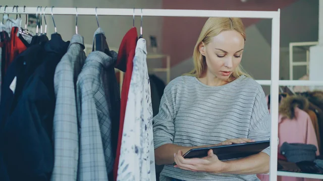 Shop owner reviewing clothing inventory on a tablet
